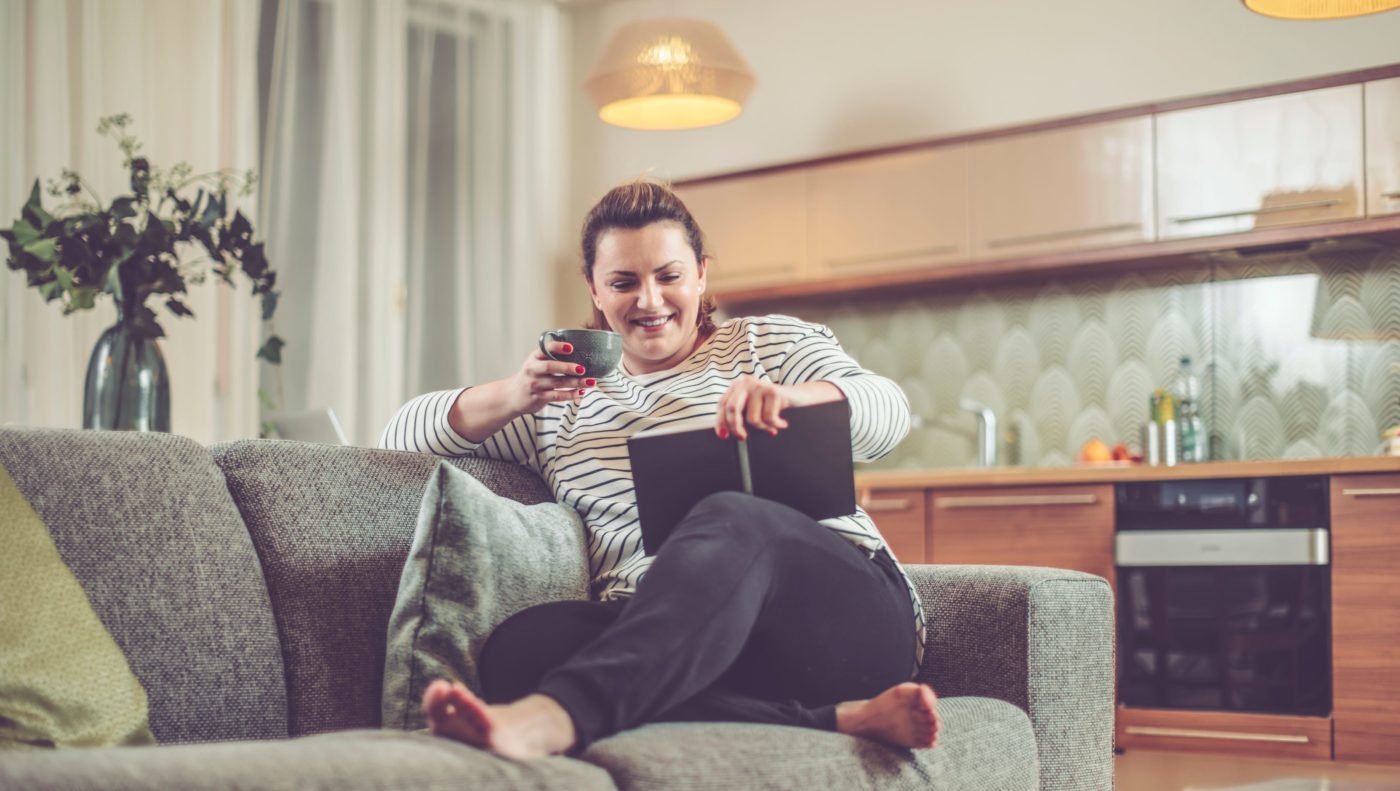 woman sitting on couch with book and coffee