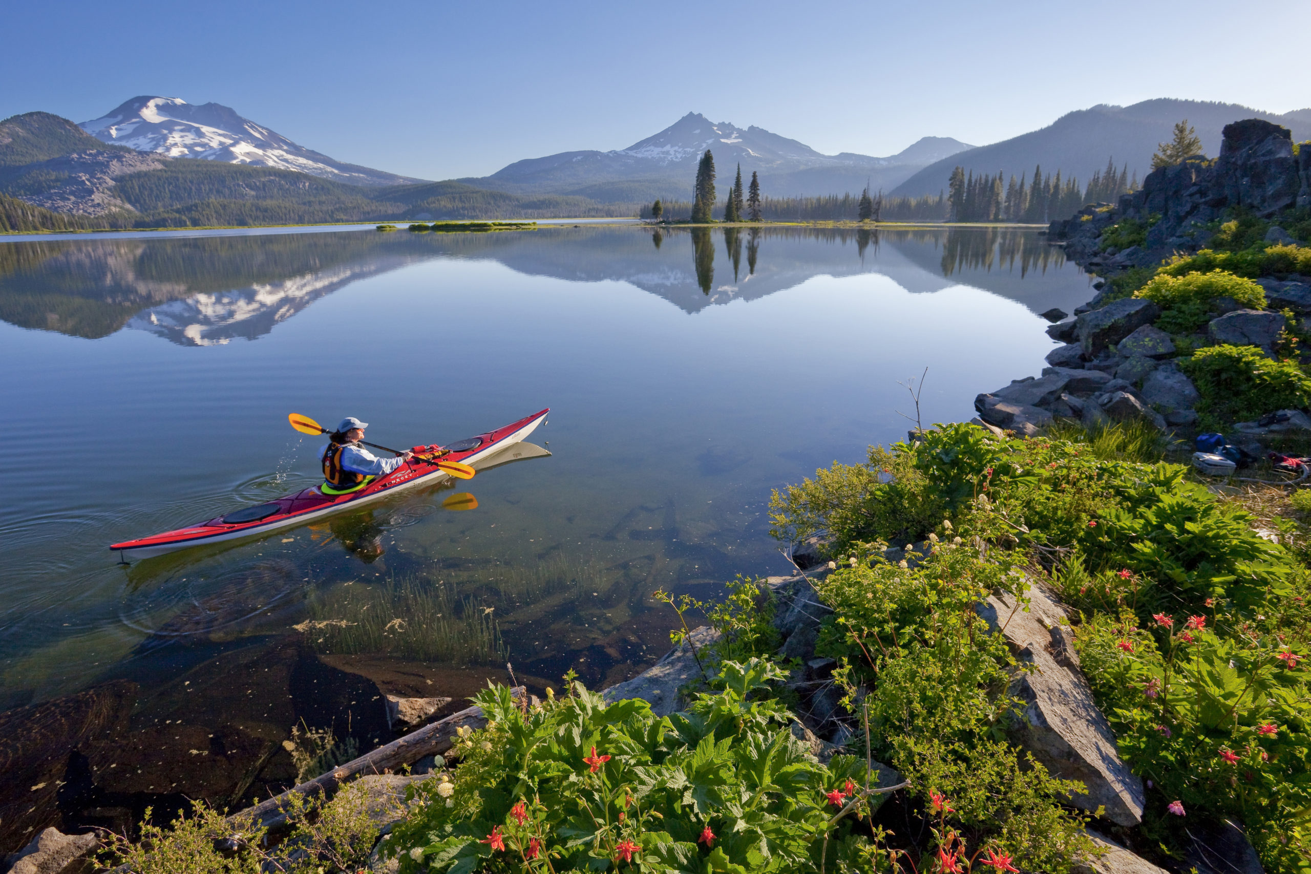 kayaker on clear lake with mountains in view