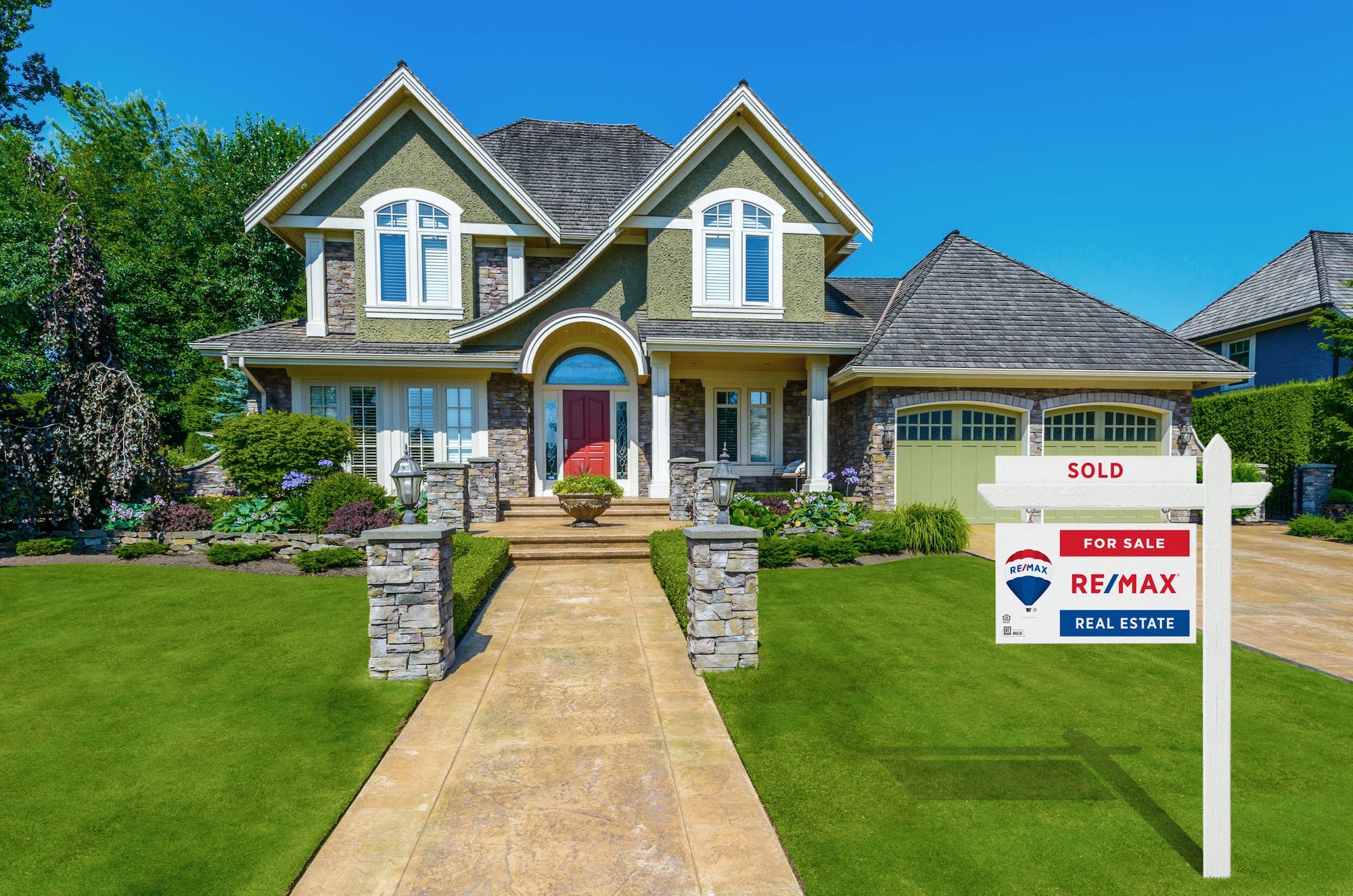 two story home with re/max sale sign out front
