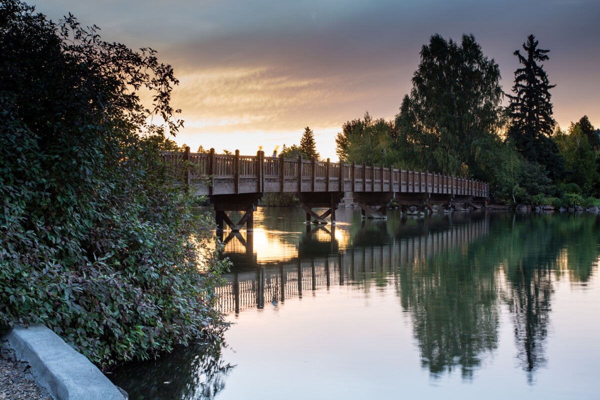 wooden bridge over mirror pond at sunset